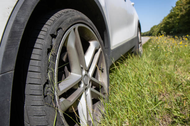 A car with a flat tyre after a large blow out on the highway showing a large slit in the tyre at the side of the M25 motorway in London in the UK stock photo