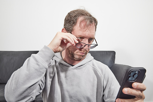 Man with glasses at home using mobile smart phone