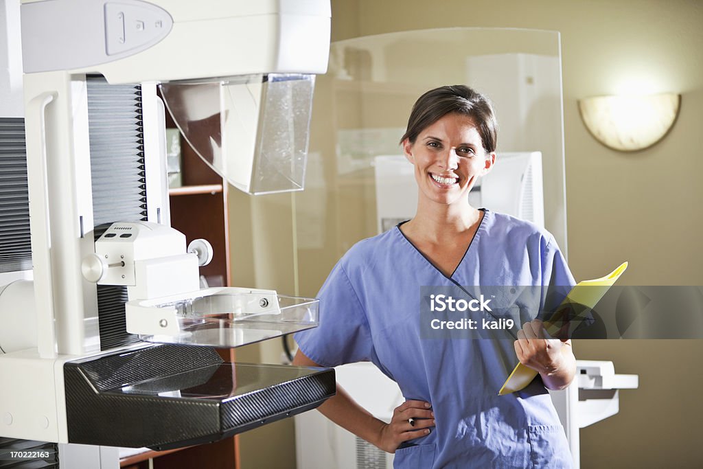 Healthcare worker with mammography scanner Nurse or technician, 20s, standing next to mammography scanner. Mammogram Stock Photo