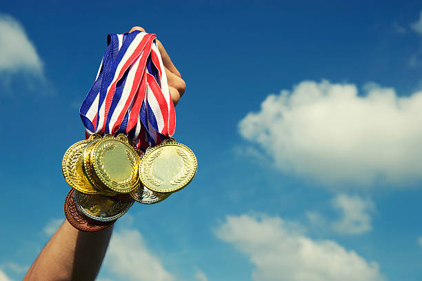 istock Gold Silver Bronze Medals Hand Holding Up in Blue Sky 170222357