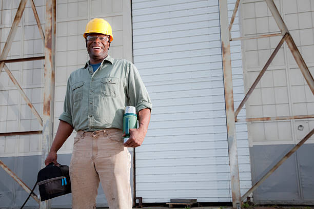 Worker with lunchbox African American worker (30s) with lunchbox and thermos, taking a break. construction lunch break stock pictures, royalty-free photos & images