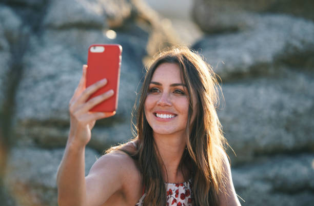 istock Beautiful woman taking photo using smartphone on beach at sunset 1702230949