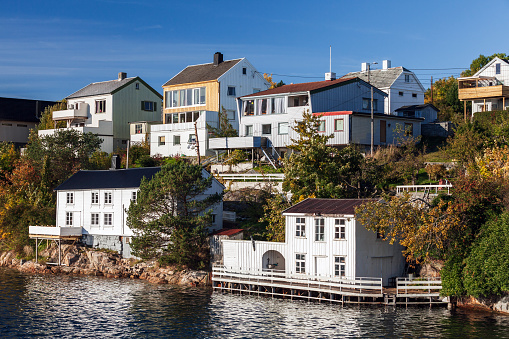 Coastal Norwegian town view with residential wooden houses under blue sky. Kristiansund seaside landscape photo taken on a sunny autumn day