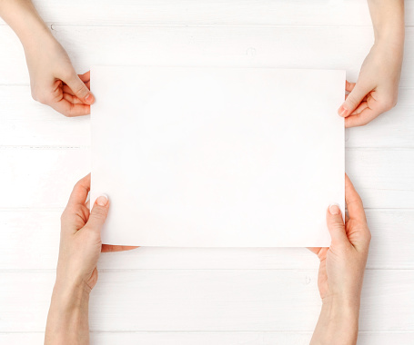 Hands of mother and daughter holding blank white paper a4 size for design