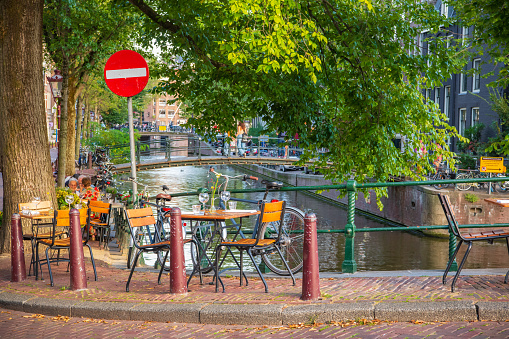 Amsterdam outdoor restaurant tables and seats on the sidewalk in the old canal district in the city center during summer.