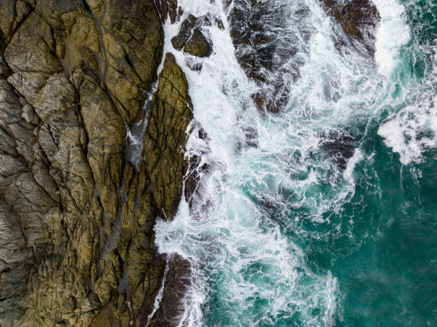 istock Waves crashing on seashore rocks,Top view sea surface waves background 1702259266