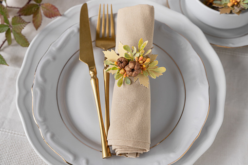 Thanksgiving napkin arrangement with mini pumpkins and leaves, autumn table decoration on plates,