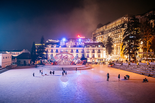 Sa pa, Vietnam - November 13, 2022: few people on huge illuminated town square with hotels in Sa pa at night