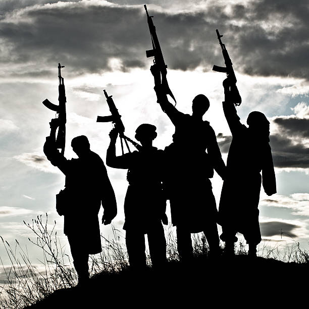 silueta de militantes islámicos con rifles - terrorism fotografías e imágenes de stock