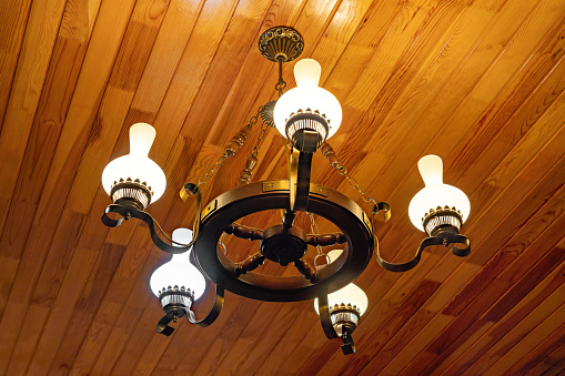 Vintage chandelier on wooden ceiling in country house