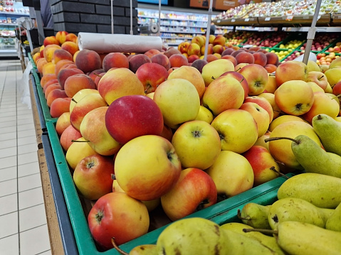 Apples in plastic boxes in a store, close-up. Ripe apples on sale, side view. Sale of fruits