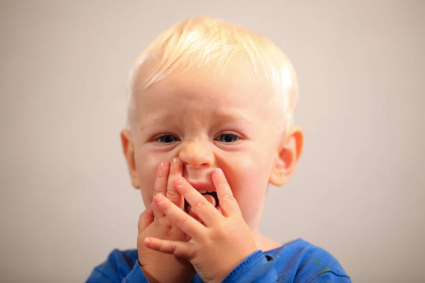istock blond baby brushes his teeth with a blue brush 1702313404