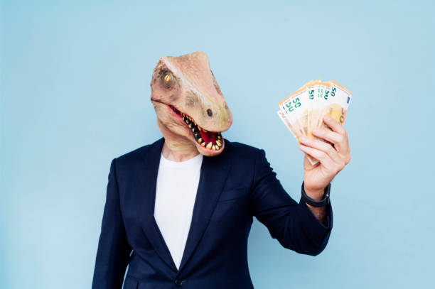 istock Attractive man with dinosaur mask holding his money 1702321541
