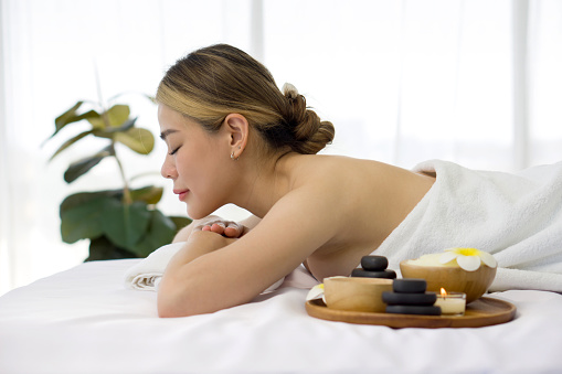 A serene woman reclining leisurely within a soothing spa ambiance, surrounded by elements promoting tranquility. Holistic luxury wellness experience. Side view