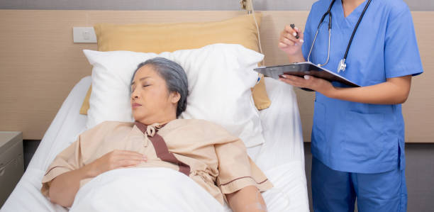 istock Asian nurse check saline and check patient elderly while asleep on bed at hospital ward, doctor diagnostic senior woman while sleep and writing report on clipboard, medical and insurance concept. 1702331472