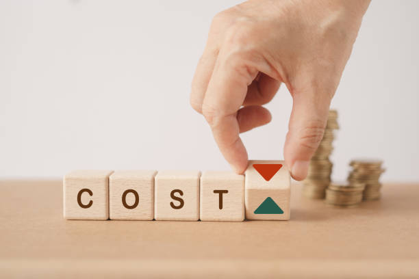 istock cost word on wooden cube blocks with hand flipped to change arrow sign and blurred stack of coins including copy space for cost reduction concept 1702333979