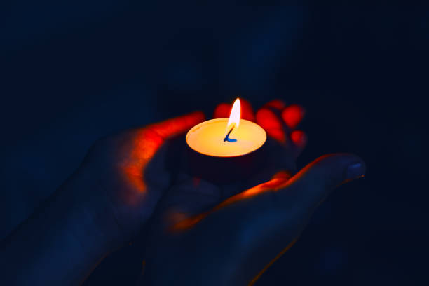 istock Candle light in the hands on a dark 1702335886