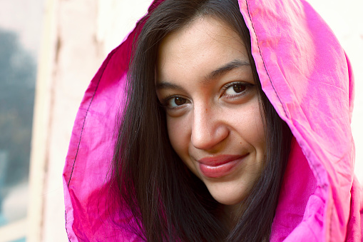 Portrait of a smiling beautiful teenage girl with a pink hood