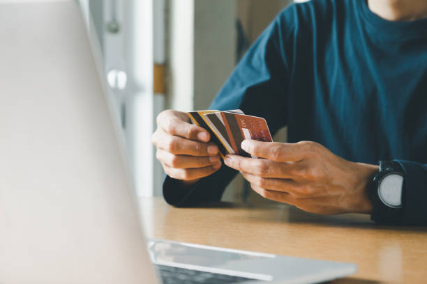 homem segurando cartão de crédito e usando laptop em casa, empresário ou empreendedor trabalhando, compras online, e-commerce, internet banking, gastar conceito de dinheiro. - junts pel sí - fotografias e filmes do acervo