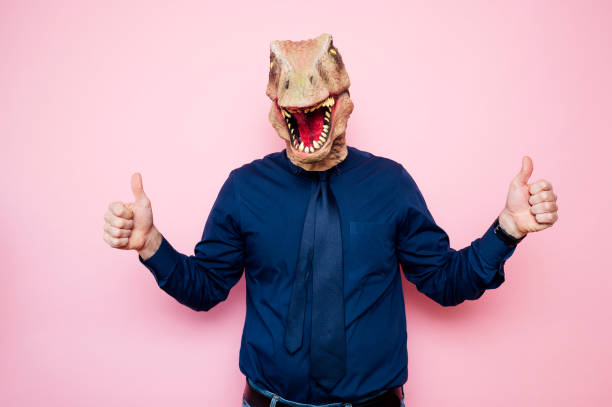 istock Man with euphoric dinosaur head and fingers up 1702356956