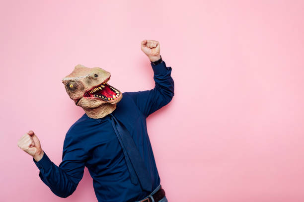 istock Euphoric man with dinosaur head with raised fists 1702360055