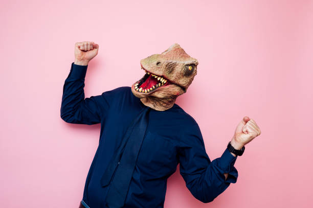 istock Euphoric man with dinosaur head with raised fists 1702360589