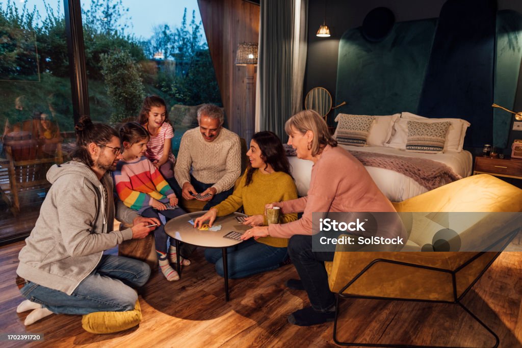 Family Board Game Extravaganza A medium shot of a multigenerational family of six playing a card game on a winter's day in the North East of England. They are on a staycation holiday and staying in a luxurious holiday home.

 There is video to match this scenario. Family Stock Photo