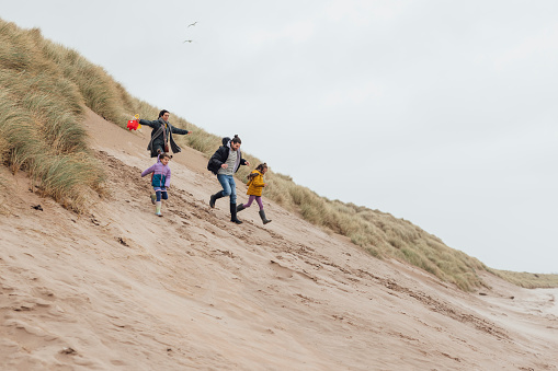 A family's beach adventure comes to life as parents walk alongside their two daughters on the shores of Alnwick. With the sea as their backdrop, they share a special day of exploration, creating lasting memories of togetherness and seaside joy.\nThere is video to match this scenario.
