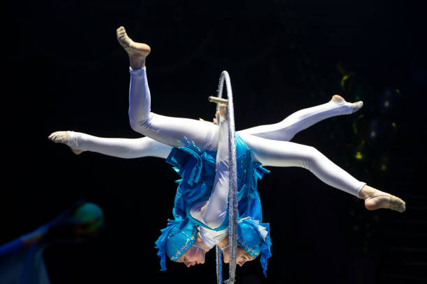 istock Two acrobat girls show a circus number on a dark background. Acrobatic performance. 1702402380