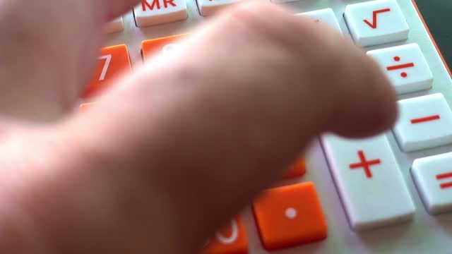 Man's Fingers Pressing Buttons on an Orange and White Calculator Adding Numbers, Close Up Shot.