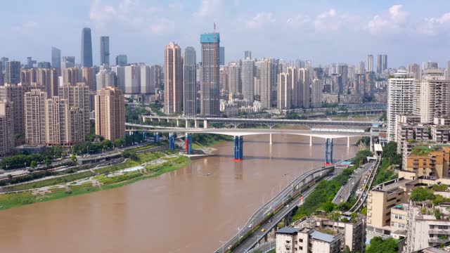 Dolly push in tilt up reveals Chongqing city china skyline and murky brown river, blue sky day aerial