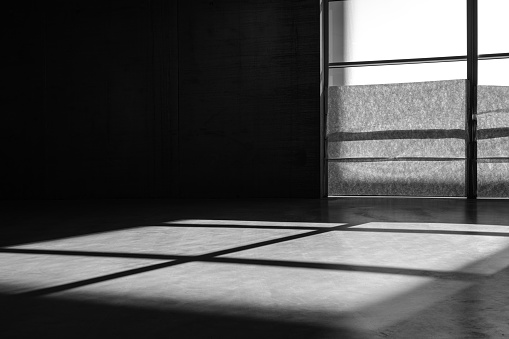 Abstract architecture background, empty dark room with window and shadow on concrete floor.