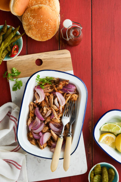 istock Pulled bbq chicken with baked onions on serving platter, bbq corn, pickles, chili peppers and buns for hot dogs and burgers, tomato sauce. Traditional American grilled summer bbq sandwiches dishes. 1702430754