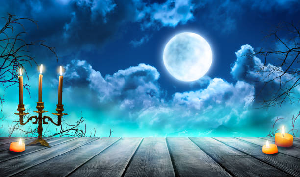 istock Smoke and mist on old wooden table with candles, defocused Halloween backdrop. 1702433949