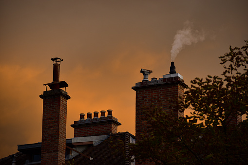 A smoke is coming out of a chimney of a building in the evening