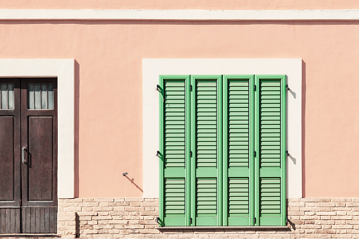 House on the street with green shutters and pink walls, detail facade