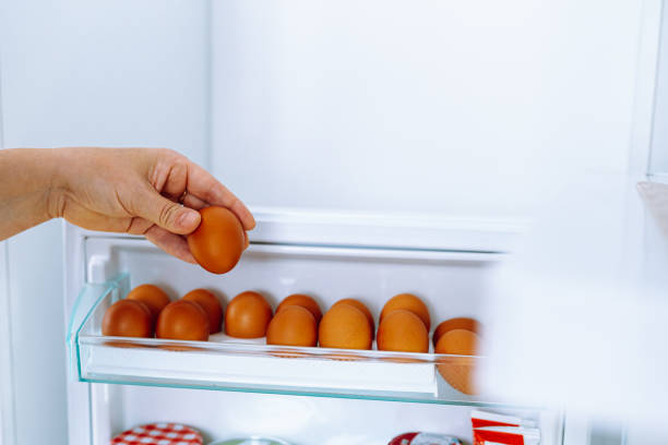 istock Closeup human hands put chicken eggs in egg-laying compartment in refrigerator 1702467132