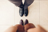Top view of couple's shoes. Man wearing black leather chelsea woman wears burgundy boots. Close up
