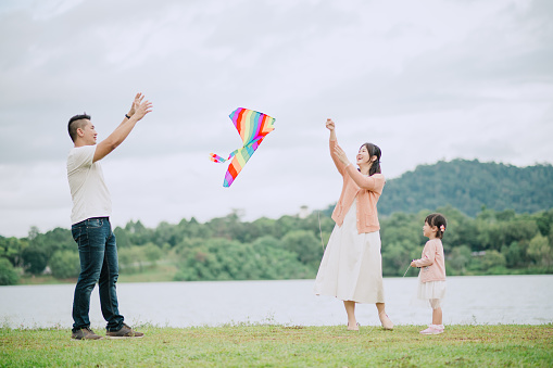 Asian Chinese family flying a kite at public park