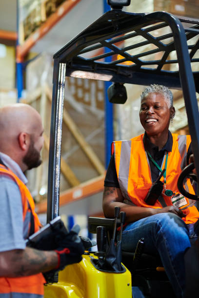 istock female fork lift driver with colleague 1702491169