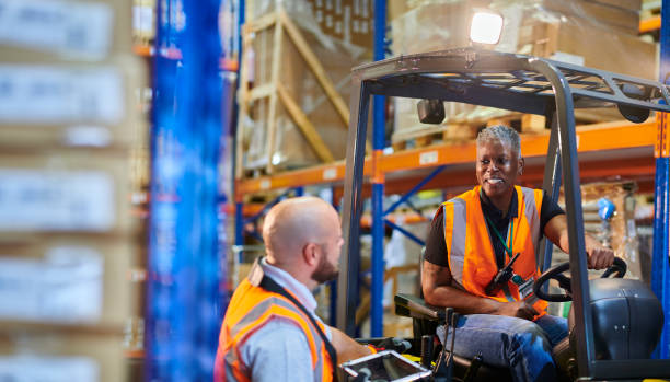 istock female fork lift driver with colleague 1702491499
