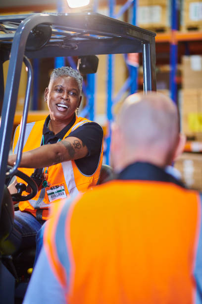 istock female fork lift driver with colleague 1702491586