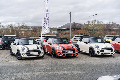 Stoke, Stoke-on-Trent, England, March 17th 2023. A row of Minis in showroom parking lot, automotive, lifestyle and business editorial illustration.