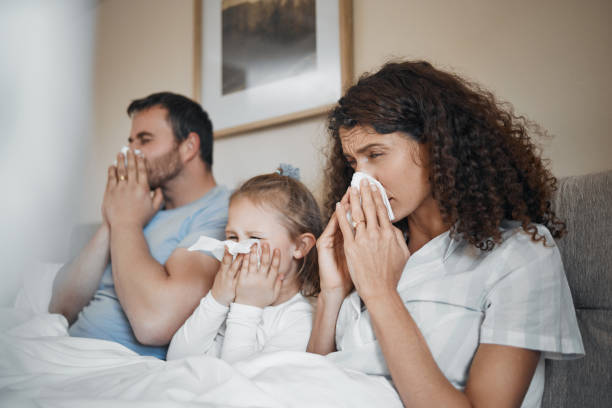 부모, 소녀, 티슈가 있는 침대, 코를 푸는 것, 집에서 알레르기, 독감 또는 코로나바이러스와 함께 아플 수 있습니다. 아버지, 어머니, 딸은 화장지, 집에서 재채기를 위한 청소, 위생을 하고 있다 - fever illness bed 20s 뉴스 사진 이미지