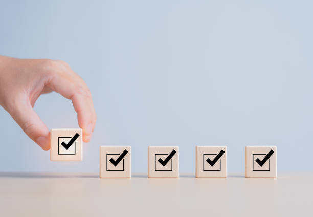 istock Task Checklist, List survey, and assessment form online. Hand holding a wooden cube with Checkmark and box for jobs list icon on wooden blocks. Company objective achievement and business success. 1702492234