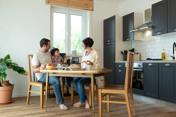 istock Cheerful family with one child having lunch at table in their kitchen. 1702492480