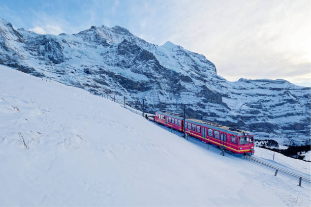 晴れた冬の日、観光客はユングフラウヨッホ(ヨーロッパのトップ)から、スイスのベルナーオーバーラントにあるユングフラウを背景にした雪に覆われた丘の中腹にあるクライネシャイデッ� - non urban scene railroad track station day ストックフォトと画像