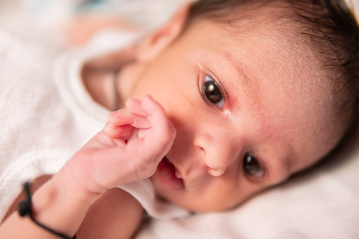 Close-up portrait of cute little newborn baby lying on the bed.