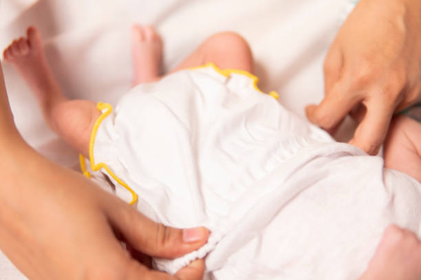 istock Mother changing her new born baby clothes. 1702495634