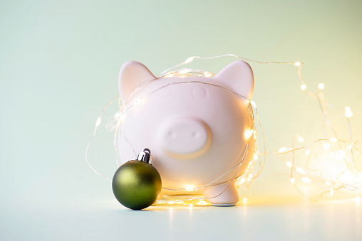 Piggy bank and Christmas ornament over green background.